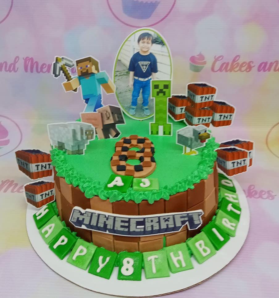 Minecraft themed birthday cake with green grass icing, brown block sides, and various character printouts including Steve and a Creeper.