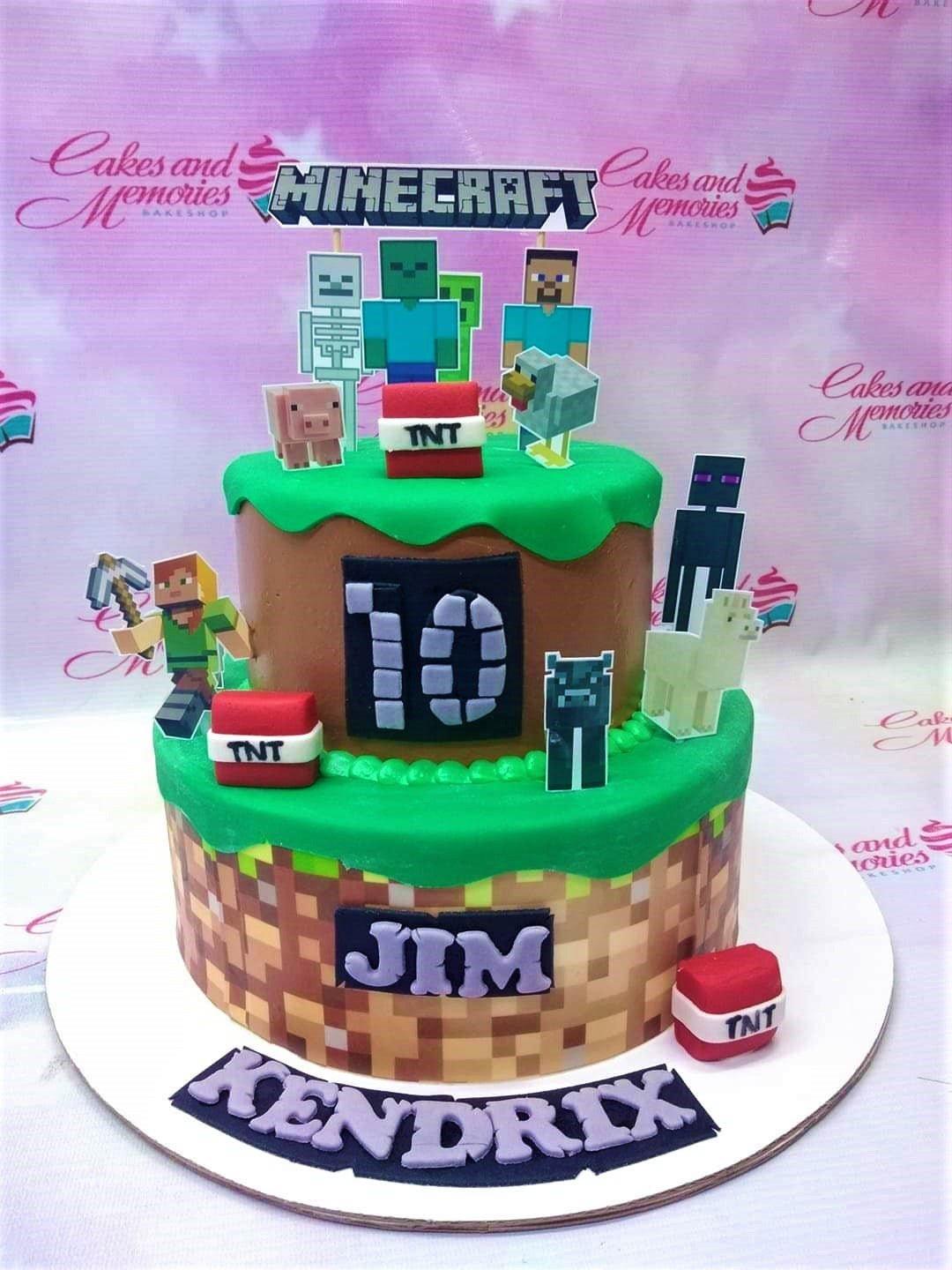 Two-tier Minecraft themed birthday cake with green grass fondant, brown dirt blocks, and various character printouts including Steve and zombies.