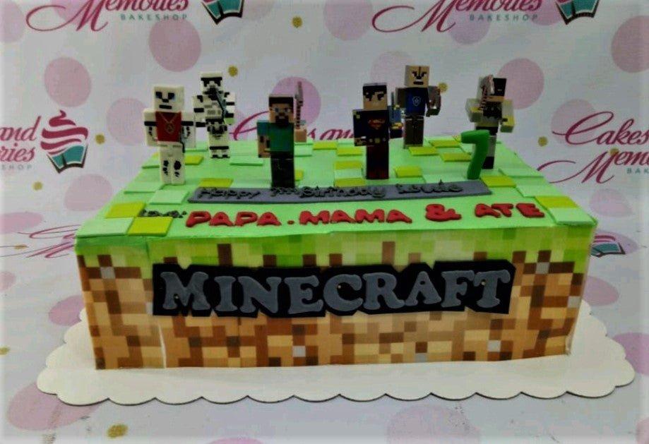 Minecraft themed rectangle cake with green grass icing, pixelated dirt sides, and various character printout toppers for a 7th birthday.