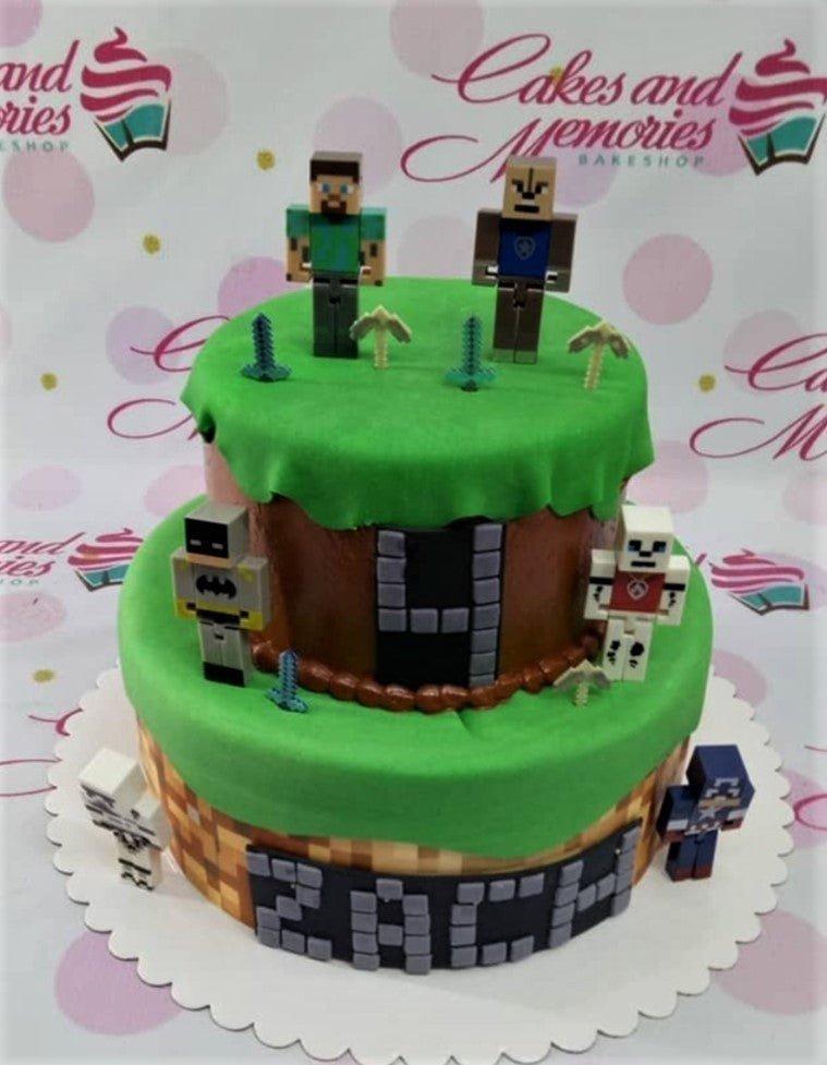Two-tier Minecraft themed cake with green fondant grass, brown dirt sides, and various character figurines including Steve and Batman.