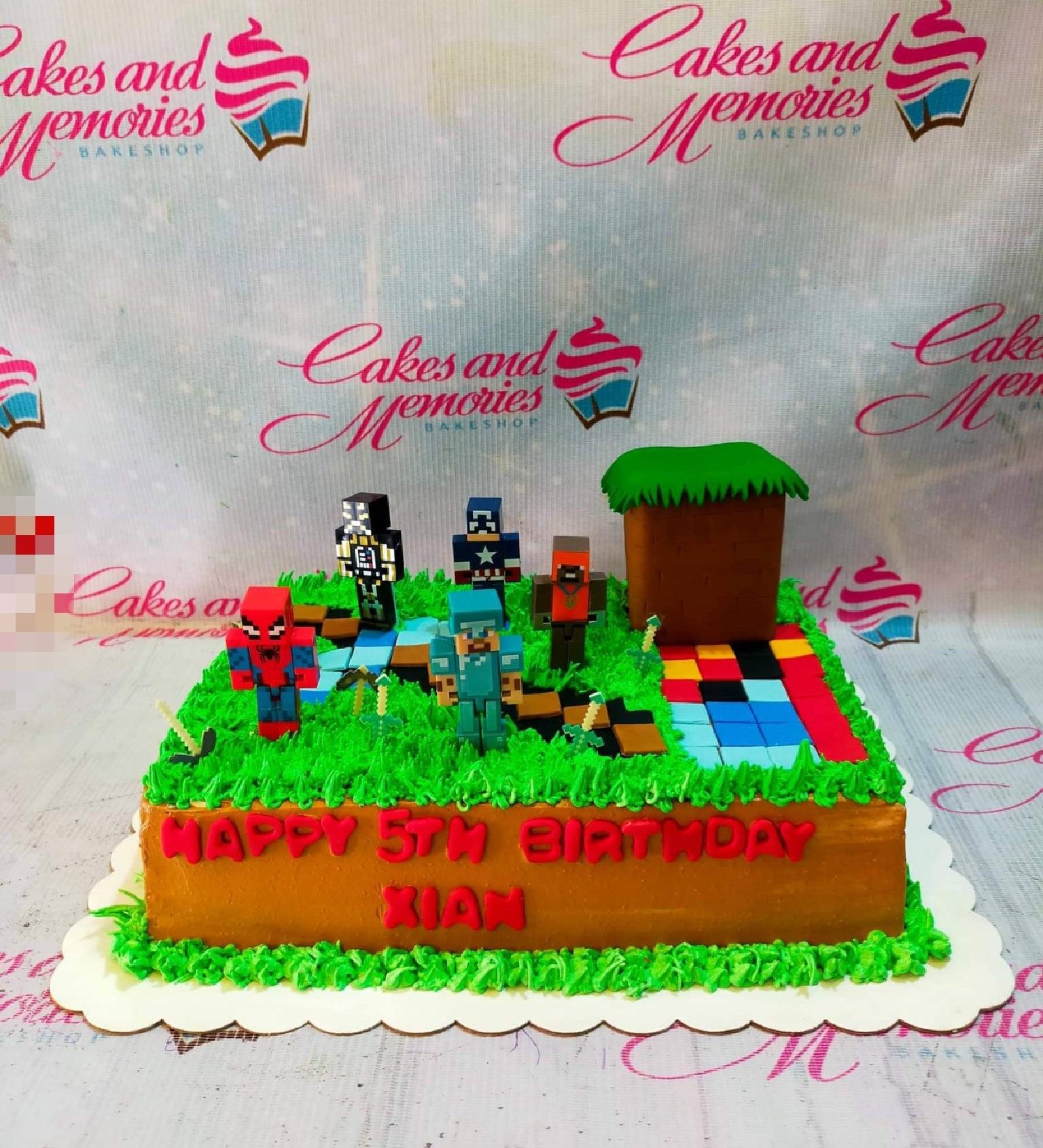 Minecraft and superhero themed rectangle cake with green grass icing, pixelated characters, and a brown block structure.
