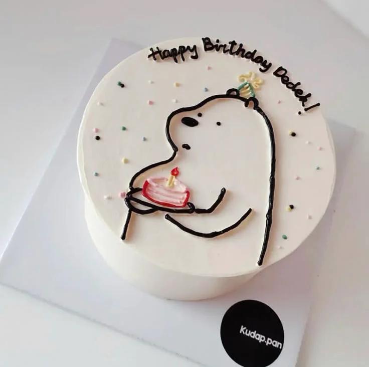 White bento cake featuring a minimalist hand-piped icing doodle of a bear holding a small pink cake with a candle.