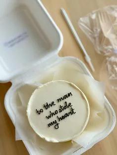 White minimalist bento cake with black piped icing text in a white takeout container
