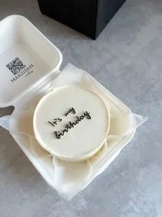 White minimalist bento cake with black cursive icing text saying it's my birthday in a white takeout box