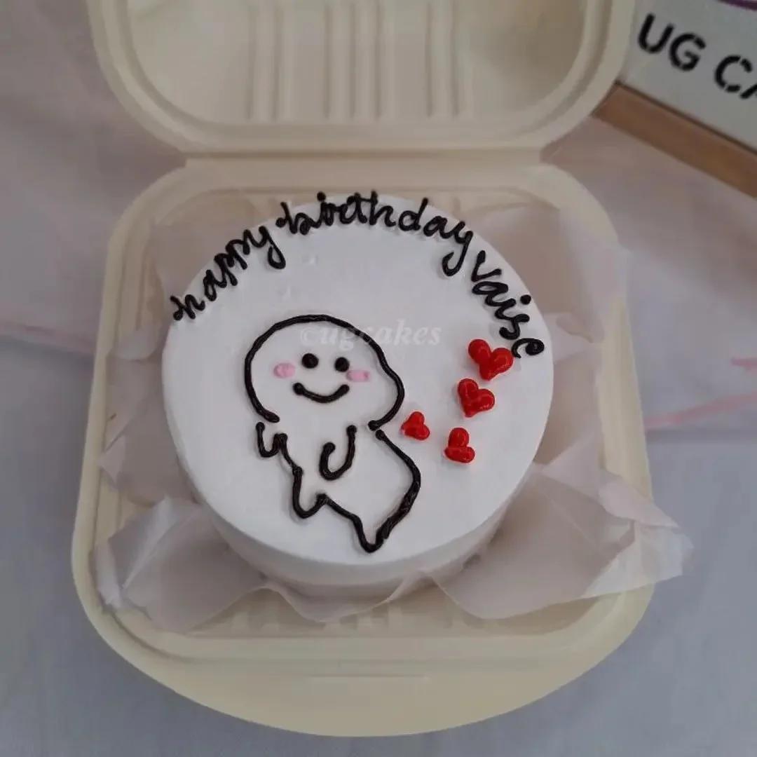 White bento cake with a minimalist doodle character holding red hearts and a Happy Birthday Vaise message.