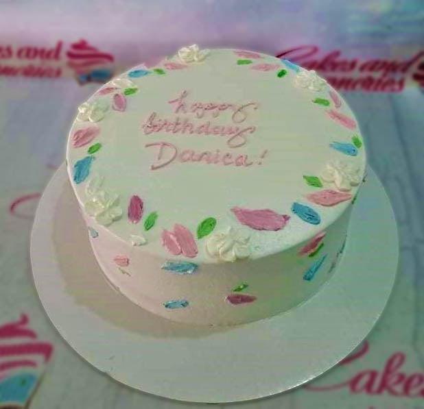 White minimalist bento cake with pink, blue, and green palette knife icing flowers and a pink birthday message.