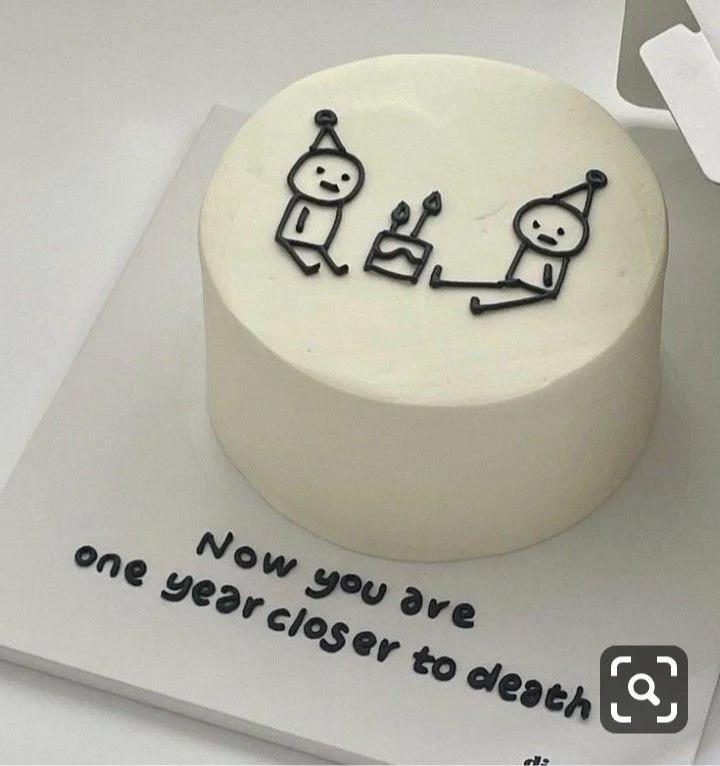 Minimalist white bento cake with black piped stick figures and a humorous birthday message on the board.