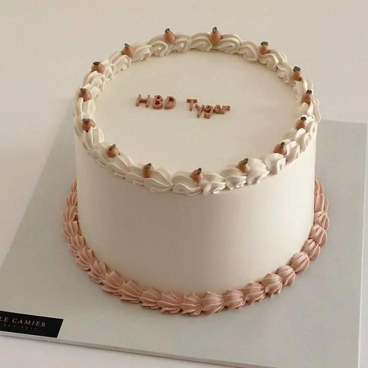 Minimalist white birthday cake with peach icing rosettes and HBD Tyger message