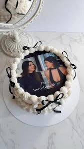 White minimalist cake with a large photo printout of two women and black ribbon accents.