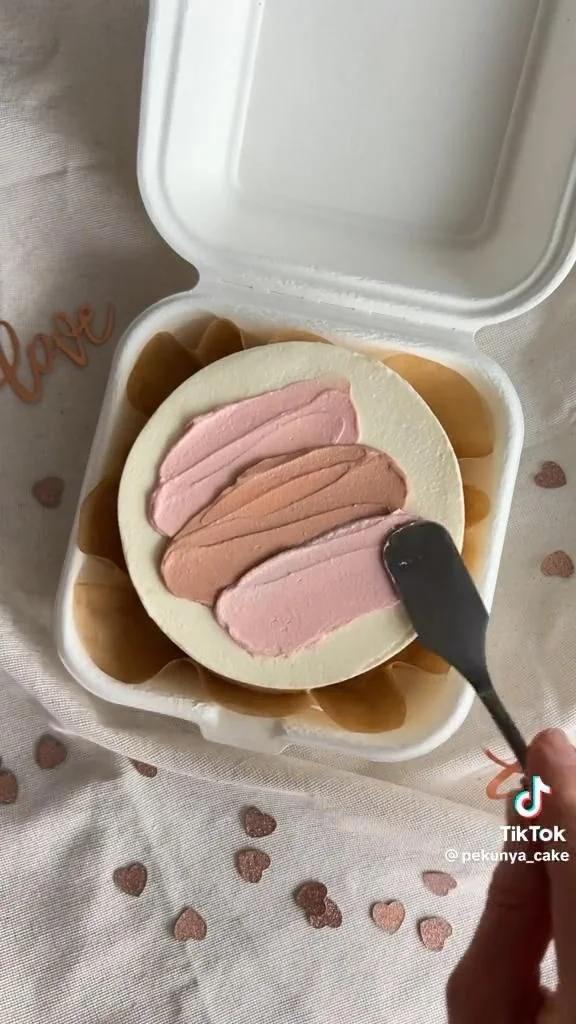 Bento cake with a minimalist palette knife icing design in shades of pink and tan on a white base.