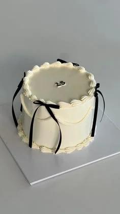 Elegant white minimalist cake with black ribbon bows and silver number 25 topper