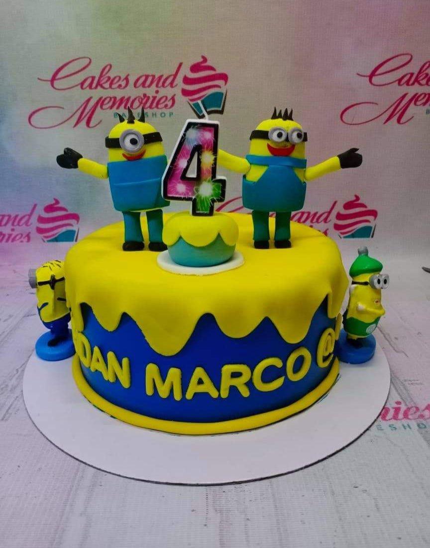 Minions themed blue and yellow fondant cake with 3D Minion figures and a number 4 candle.