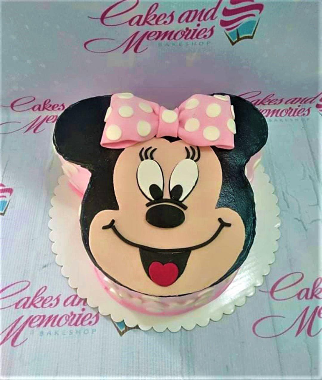 Minnie Mouse shaped cake with black icing, pink polka dot bow, and detailed fondant face features.