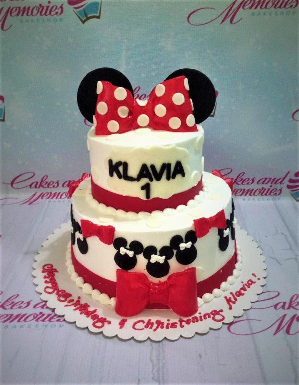 Two-tier Minnie Mouse themed birthday and christening cake in red, white, and black with fondant bows and character silhouettes.