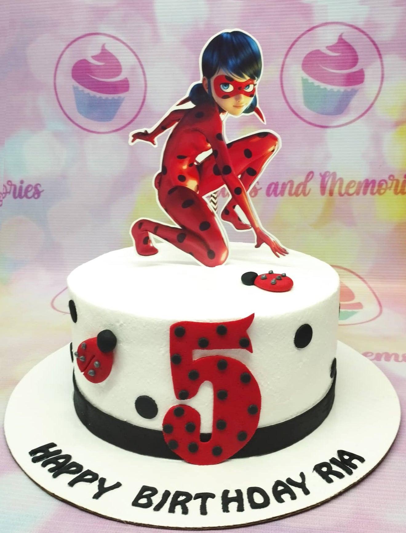 White Miraculous Ladybug birthday cake with red ladybug accents and a large character topper for a 5th birthday celebration.