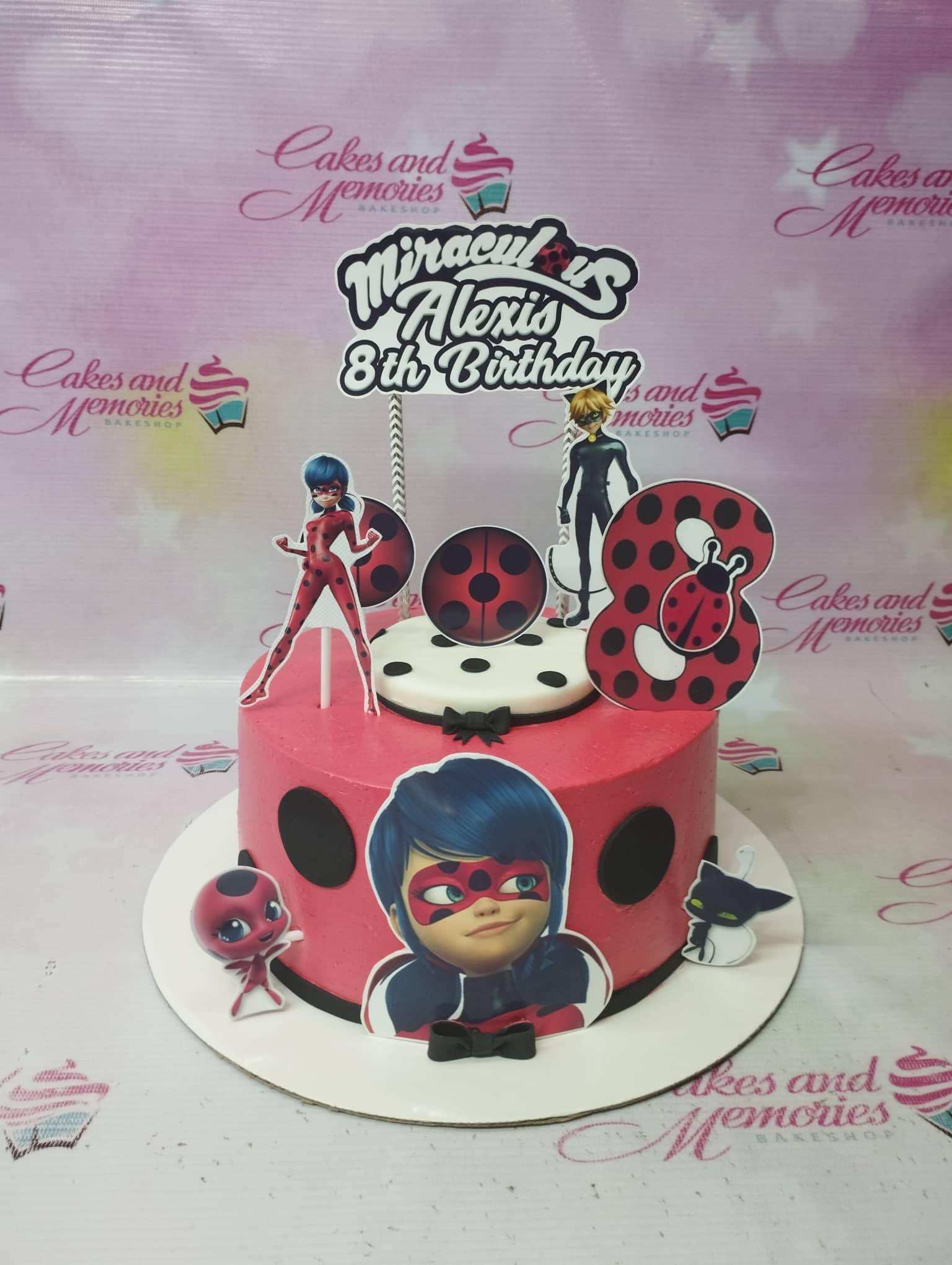 Red Miraculous Ladybug themed birthday cake with character printouts and black polka dots.