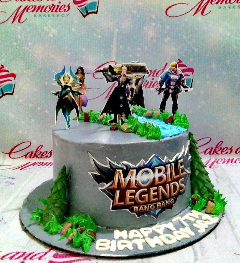 Mobile Legends themed birthday cake with gray icing, green grass piping, and character printouts for a 7th birthday celebration.