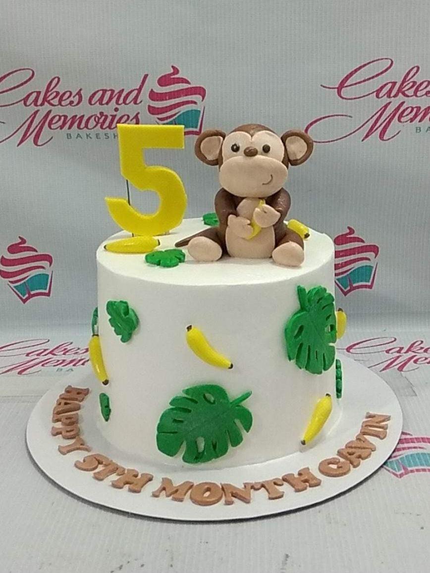 White 1-tier monkey jungle themed cake with fondant monkey, bananas, and tropical leaves.