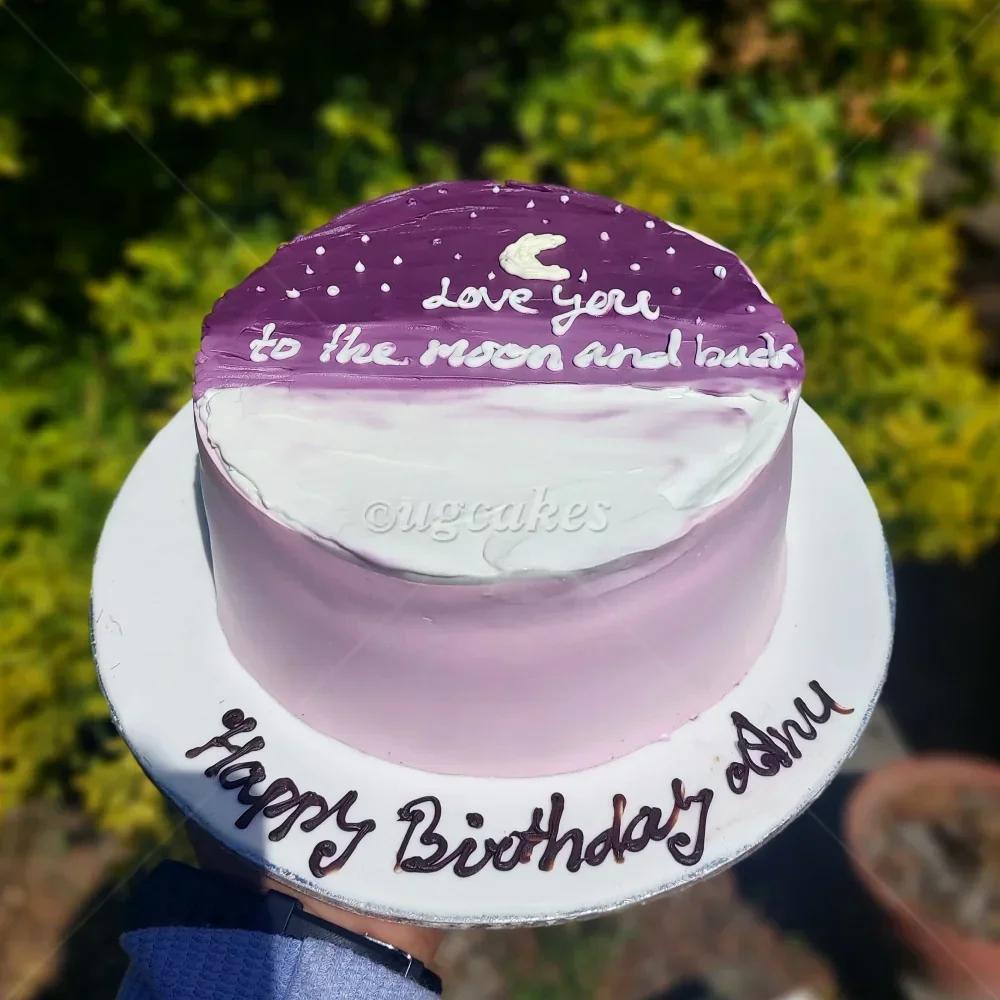 Purple and white minimalist bento cake with a crescent moon and stars design featuring the message Love you to the moon and back.
