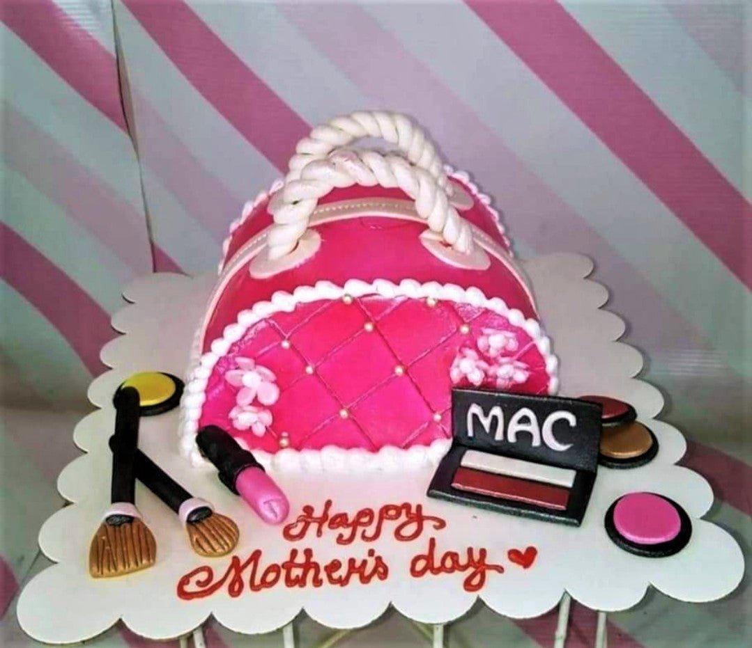 Pink handbag cake with fondant makeup accessories like lipstick, brushes, and eyeshadow palette for Mother's Day.