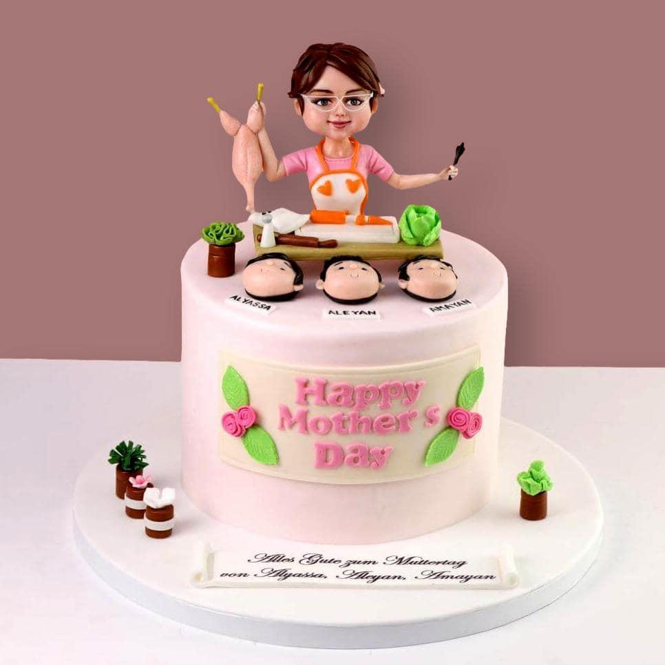 Pink fondant Mother's Day cake featuring a 3D chef figure holding a chicken, with three children's faces and a Happy Mother's Day plaque.