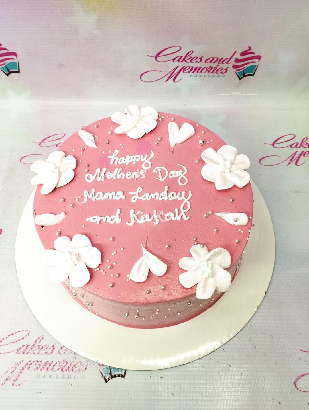 Pink minimalist Mother's Day cake with white icing flowers and silver dragees
