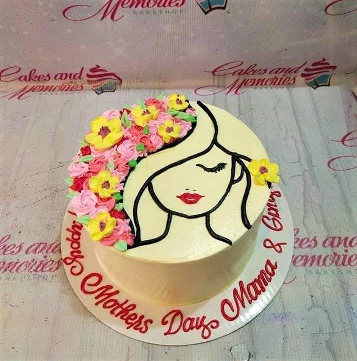 White minimalist cake with a piped icing silhouette of a woman's face and colorful floral hair for Mother's Day.