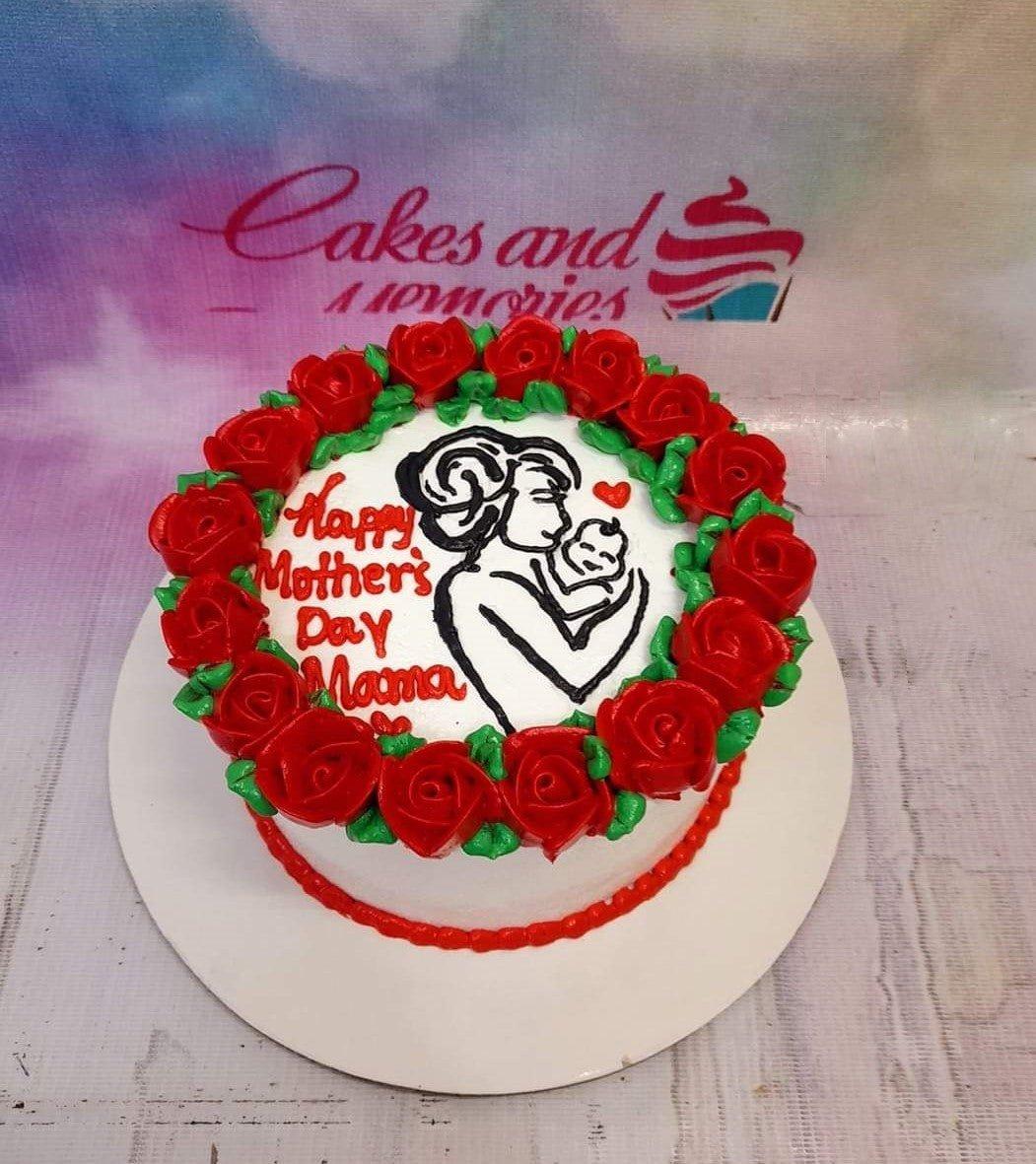 White round cake for Mother's Day featuring a piped icing illustration of a mother holding a baby, surrounded by a border of red icing roses.