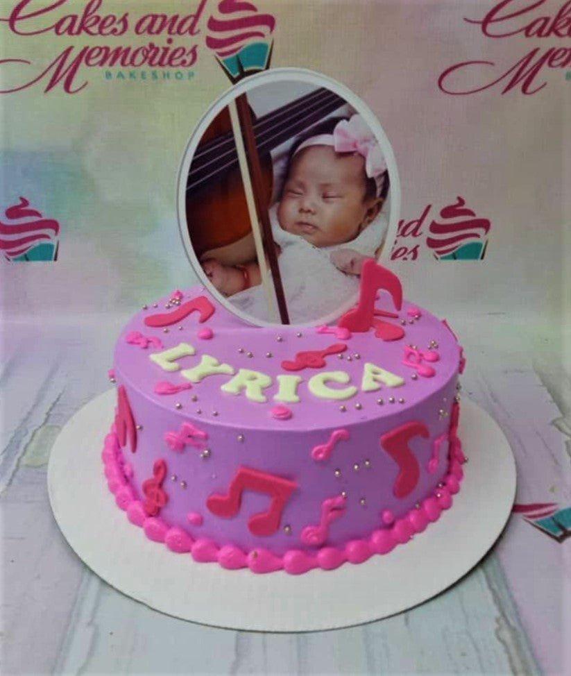 Purple music themed birthday cake with a photo printout of a baby and pink fondant musical notes.