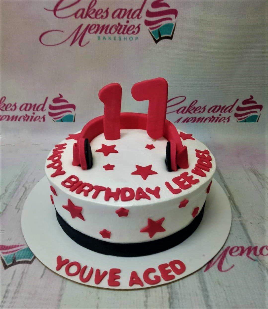 White round birthday cake with red fondant stars, red headphones topper, and red number 11 toppers.