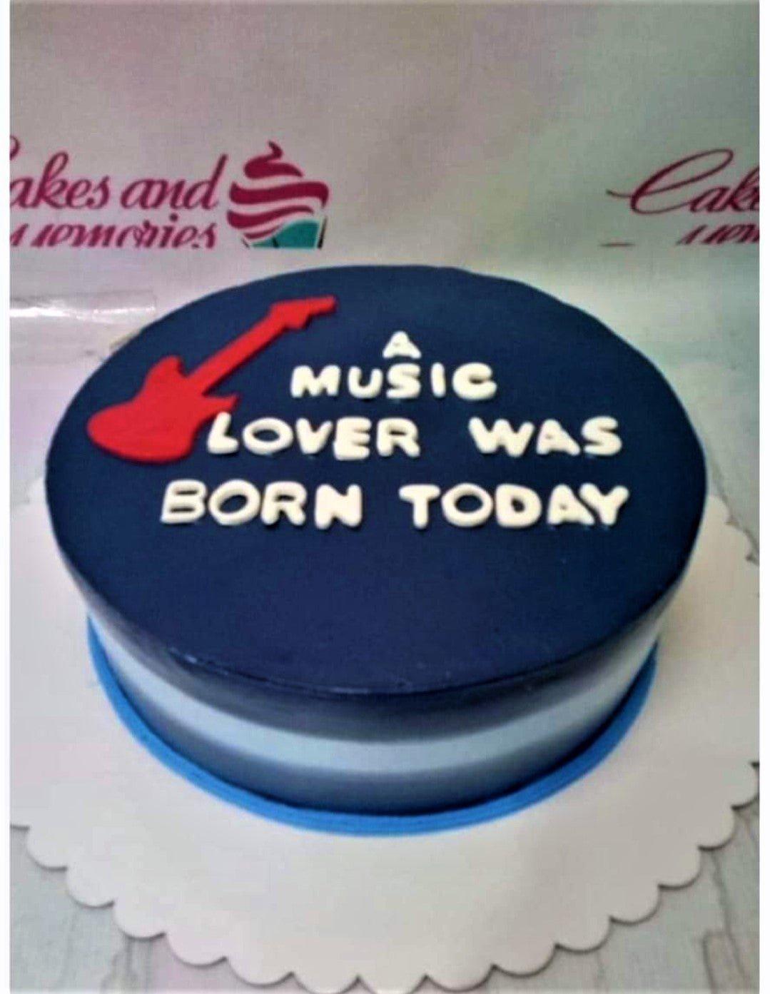 Navy blue minimalist cake with a red guitar topper and white icing message for a music lover.