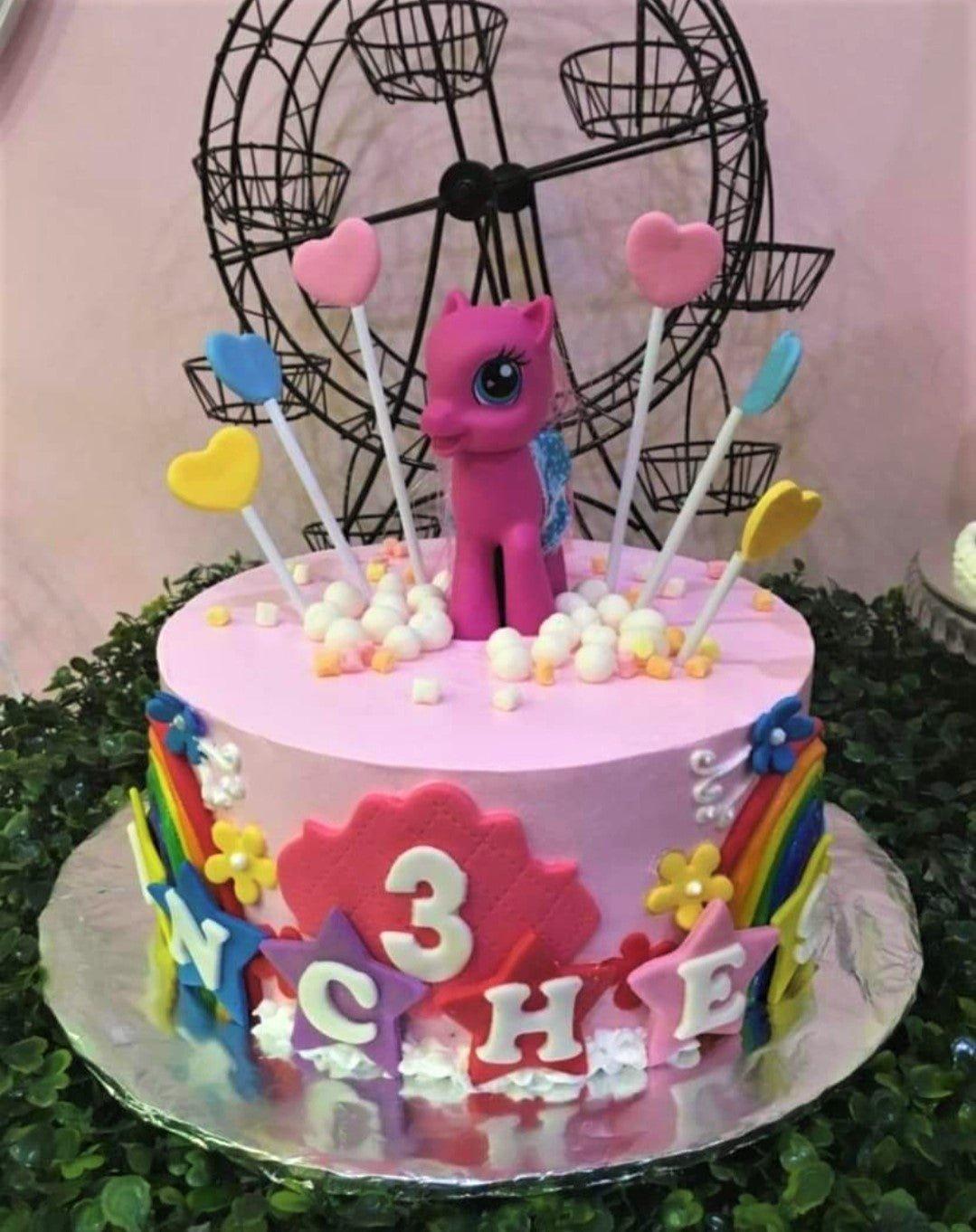 Pink My Little Pony birthday cake with a Pinkie Pie figure, rainbow side decorations, and heart toppers.