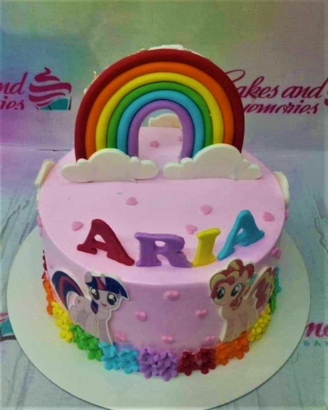 Pink My Little Pony birthday cake with a large fondant rainbow, clouds, and character printouts of Twilight Sparkle and Sunset Shimmer.