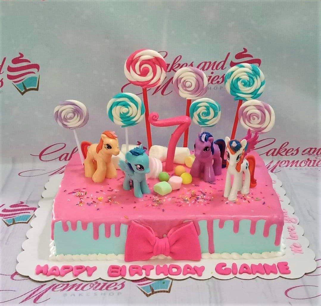Rectangle My Little Pony birthday cake with pink and light blue icing, fondant ponies, lollipops, and a pink number 7 topper.