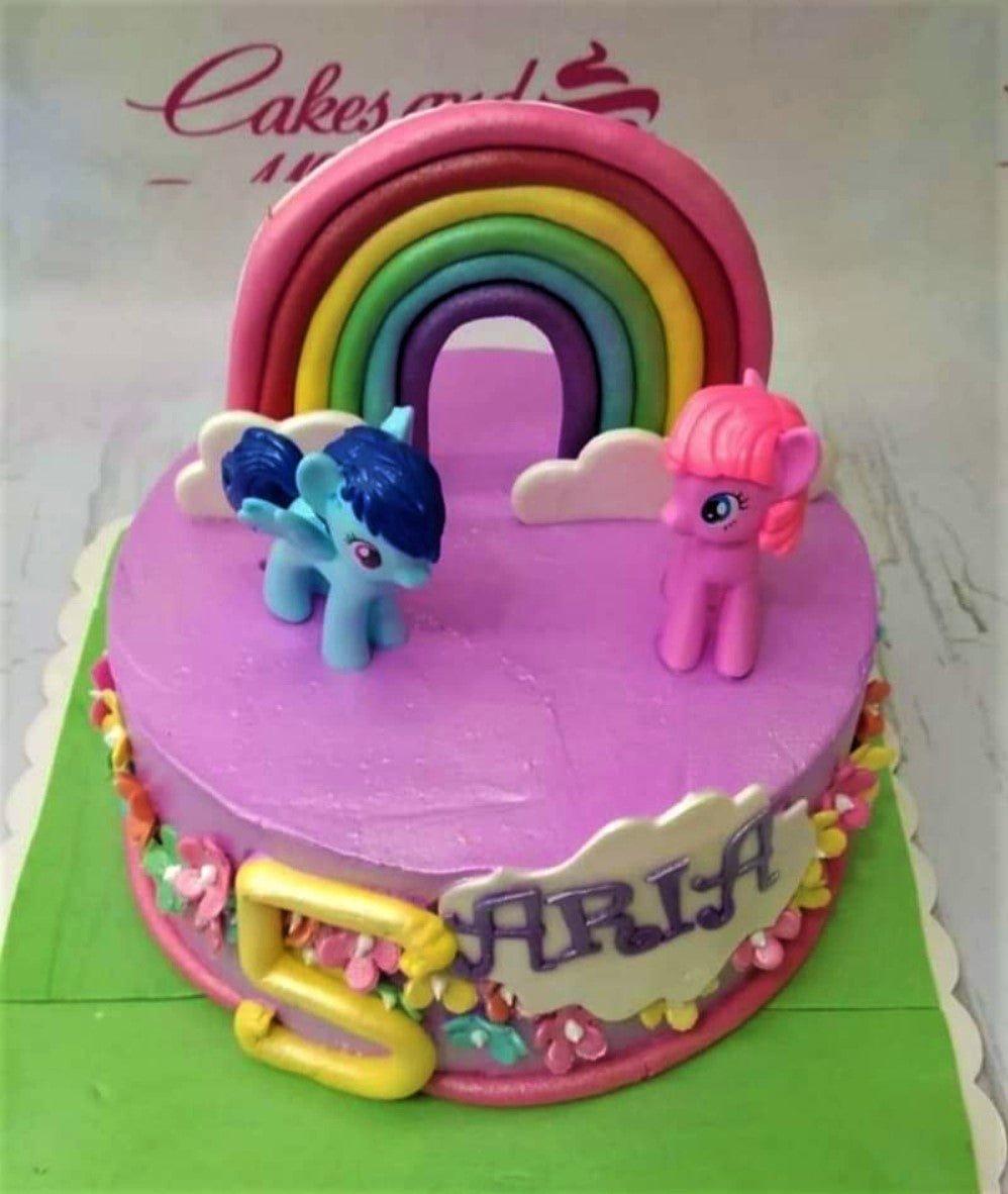 Purple My Little Pony birthday cake with a large fondant rainbow, clouds, and pony figurines.