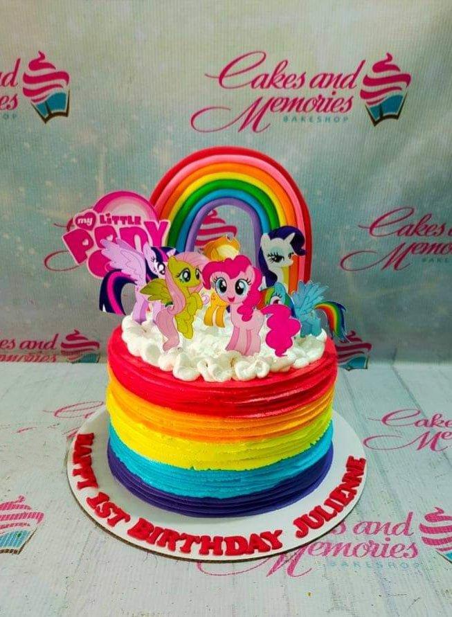 Rainbow layered 1-tier My Little Pony birthday cake with character printouts and a large rainbow topper.