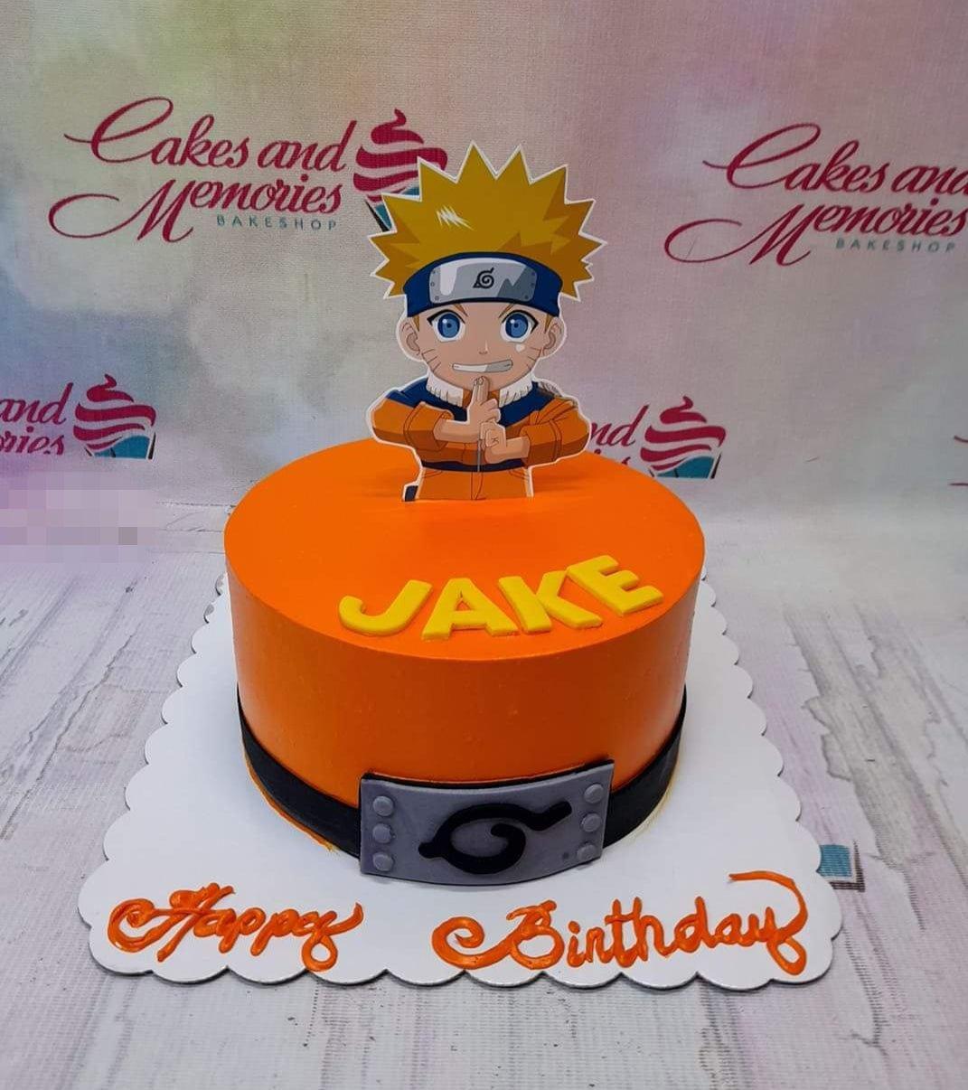 Orange Naruto themed birthday cake with a Naruto character printout topper and a gumpaste headband decoration on the side.