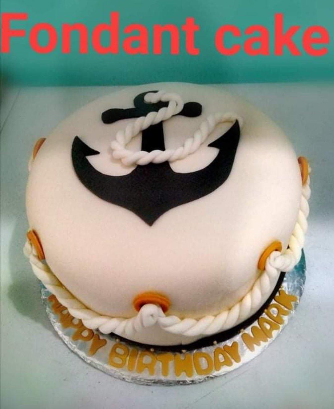 White fondant nautical cake with a large black anchor on top and white rope decorations around the base.