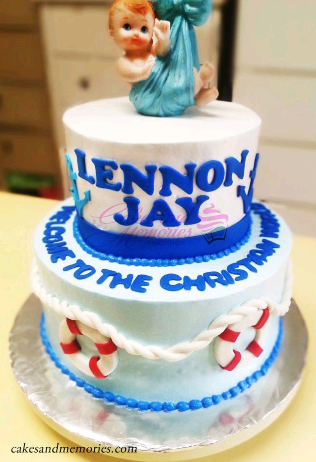 Two-tier nautical themed baby shower cake in light blue and white with a baby figurine topper and lifebuoy decorations.