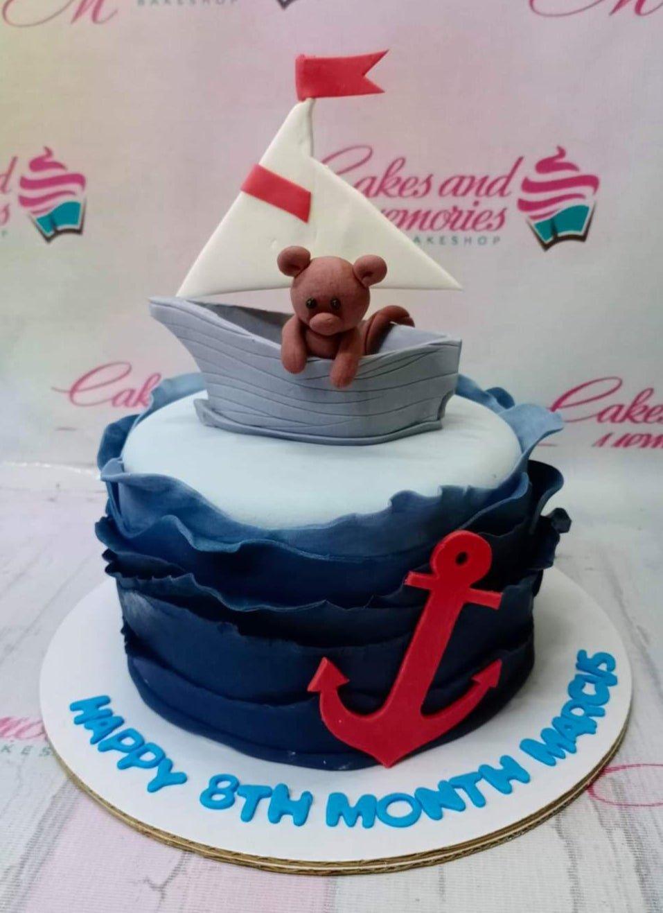 Nautical themed blue ruffle cake with a fondant boat, bear, and red anchor for an 8th month celebration.