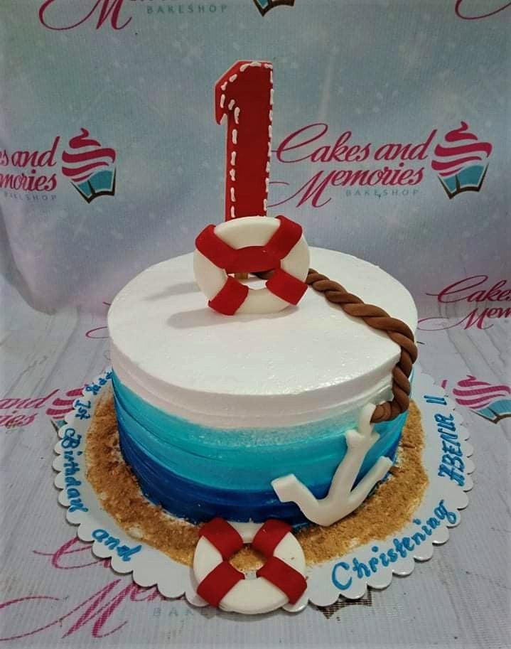 Nautical themed 1st birthday and christening cake with blue gradient icing, fondant anchor, lifebuoy, and a red number one topper.