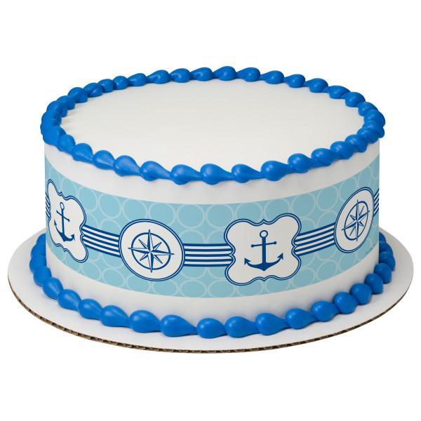Nautical themed white cake with blue anchor and compass designs and blue icing borders.