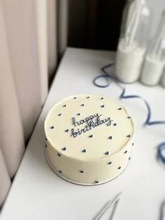 Minimalist white bento cake with navy blue piped hearts and a Happy Birthday message in cursive icing.