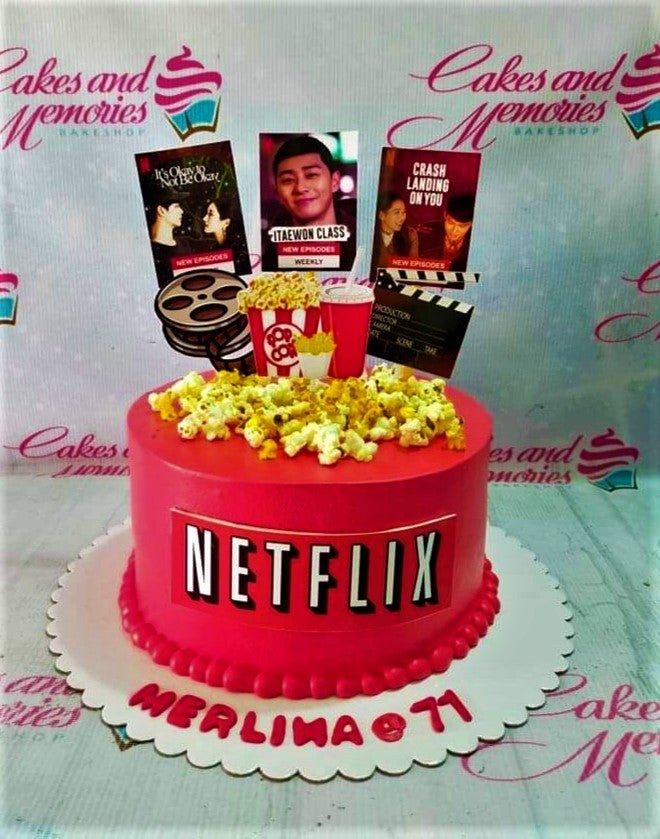 Hot pink Netflix themed birthday cake with popcorn, film reel, and K-drama poster toppers.