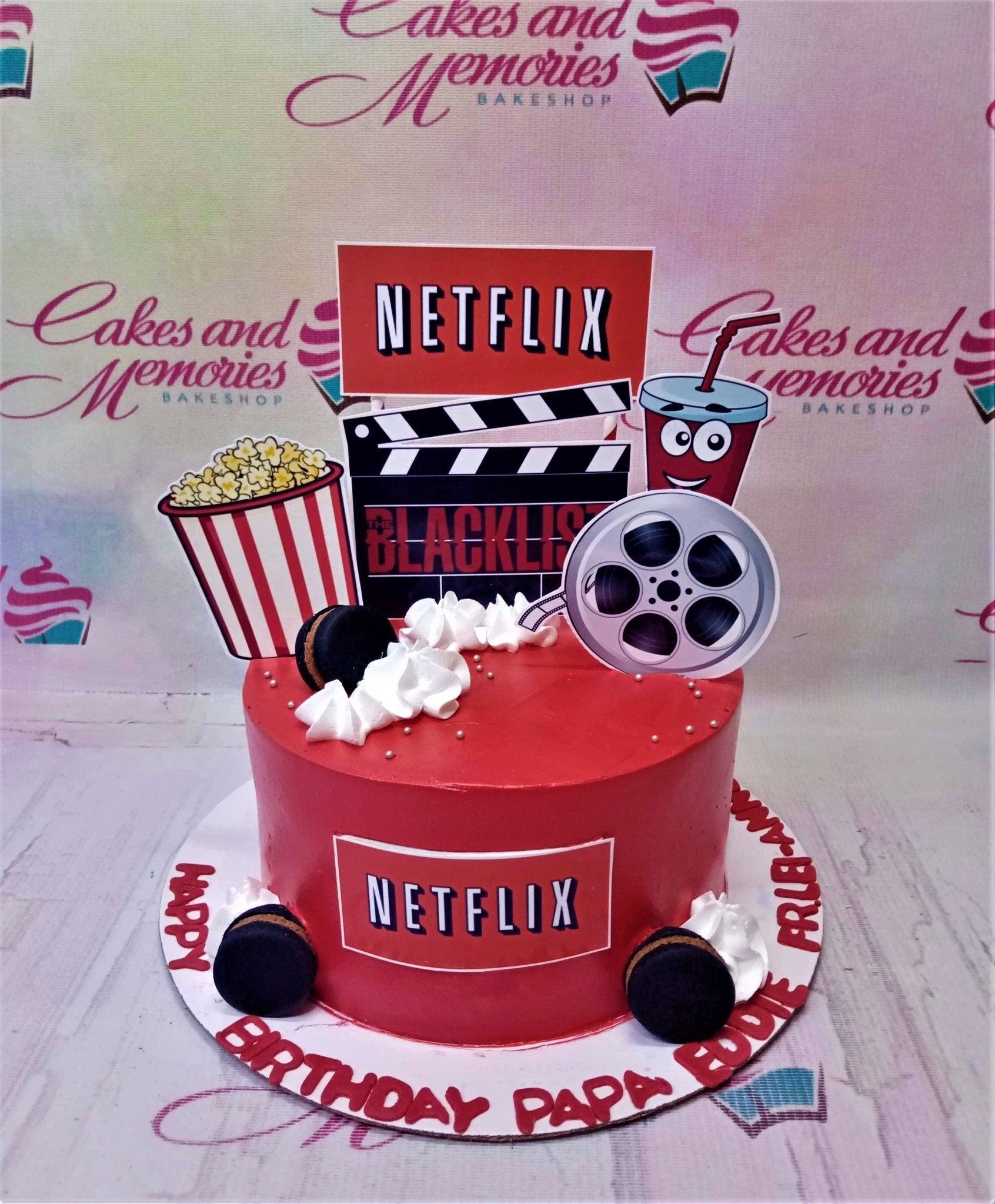 Red Netflix themed birthday cake with popcorn, film reel, and movie clapperboard toppers for Papa Eddie.