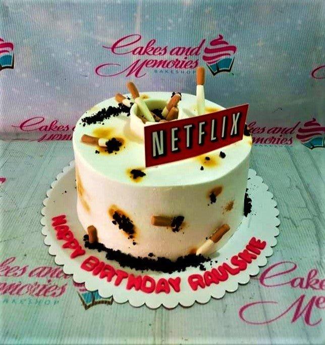 Netflix and cigarette themed birthday cake with white icing, edible cigarette butts, and a red Netflix logo topper.
