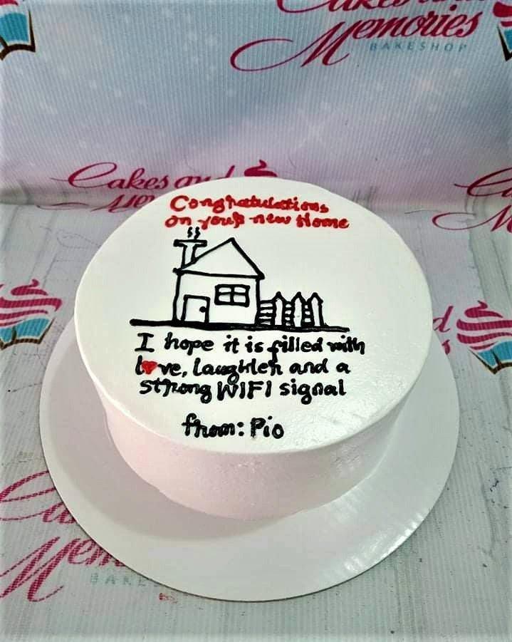 White bento cake with a hand-drawn black icing house and a humorous message about a new home and strong WiFi signal.