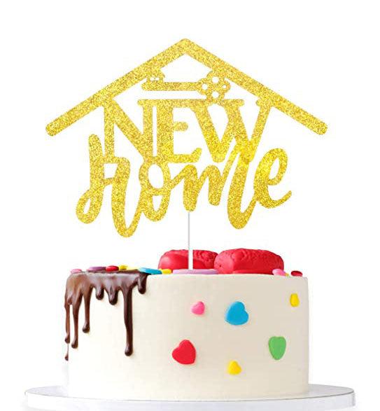 White 1-tier cake with chocolate drip, colorful heart and dot decorations, and a large gold glitter 'New Home' house-shaped topper.