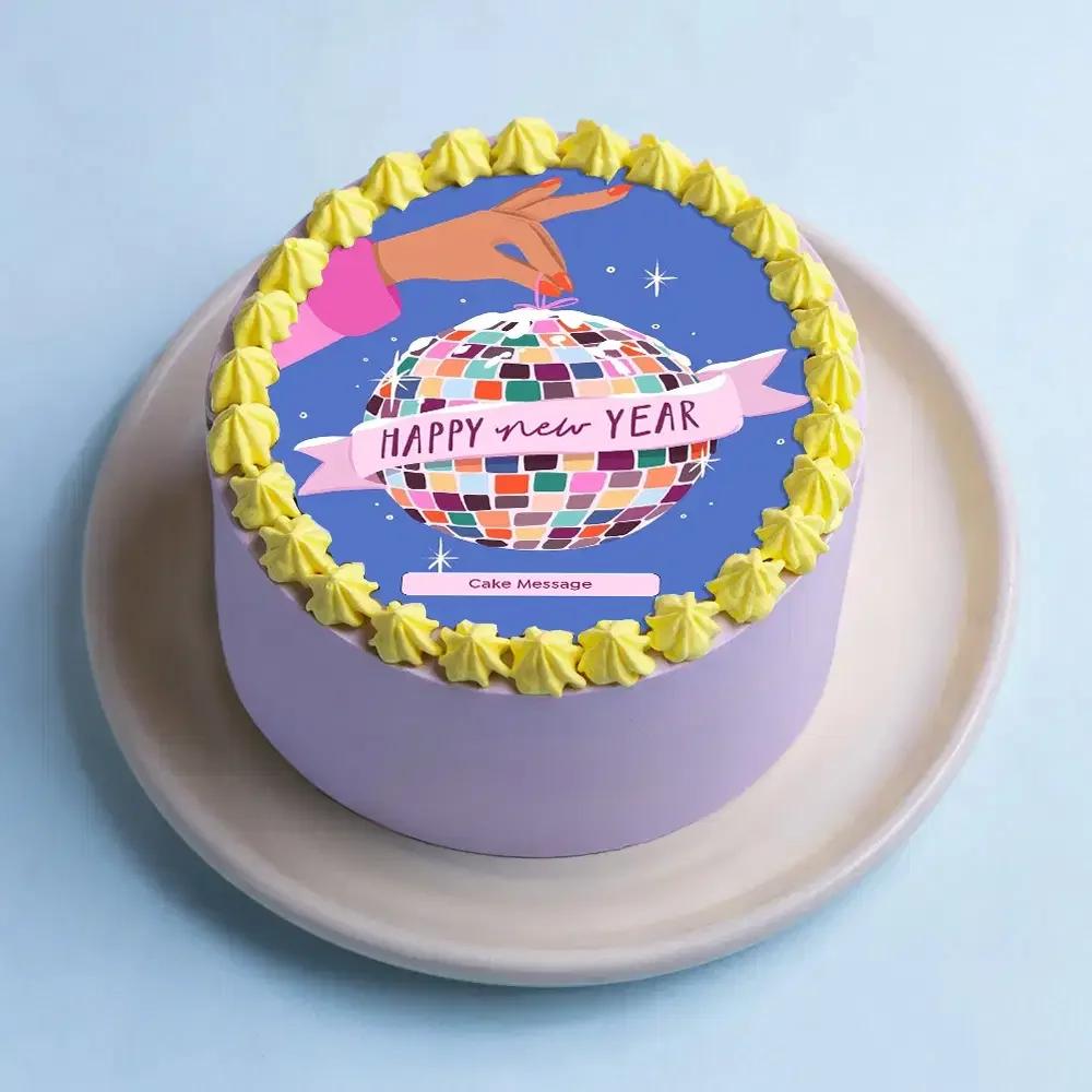 Purple bento cake with a Happy New Year disco ball printout and yellow icing rosettes.