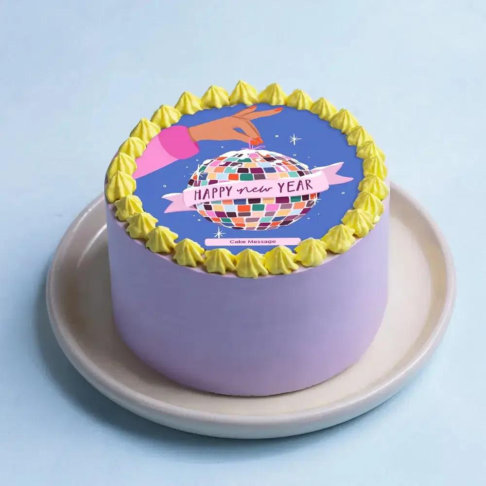 Purple New Year disco ball cake with yellow icing rosettes and a colorful printed disco ball topper.